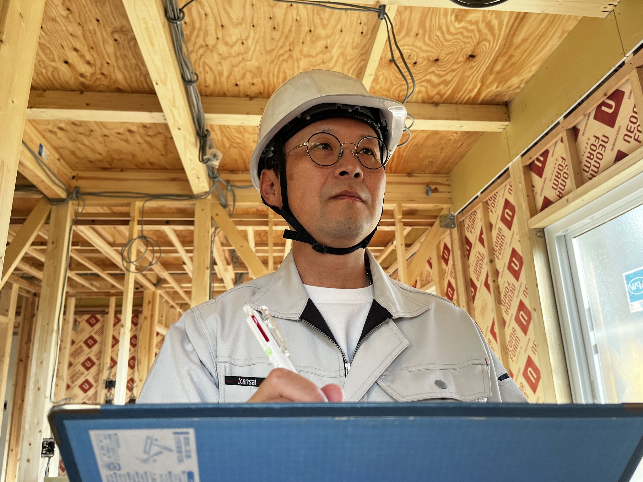 建築現場でヘルメットを着用し、資料を確認する三浦つかさ